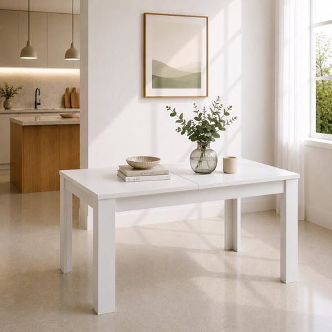 Tavolo allungabile bianco opaco con struttura lineare e gambe quadrate, inserito in un ambiente moderno e luminoso con cucina a vista, ampie finestre e arredamento minimalista