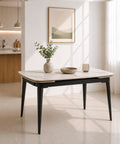 Tavolo allungabile rettangolare con angoli arrotondati, piano effetto marmo Carrara bianco e gambe effetto ghisa, inserito in un ambiente moderno e luminoso con cucina a vista e grandi finestre.