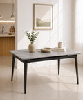 Tavolo allungabile rettangolare con angoli arrotondati, piano effetto pietra Grigia e gambe effetto ghisa, inserito in un ambiente moderno e luminoso con cucina a vista e grandi finestre.