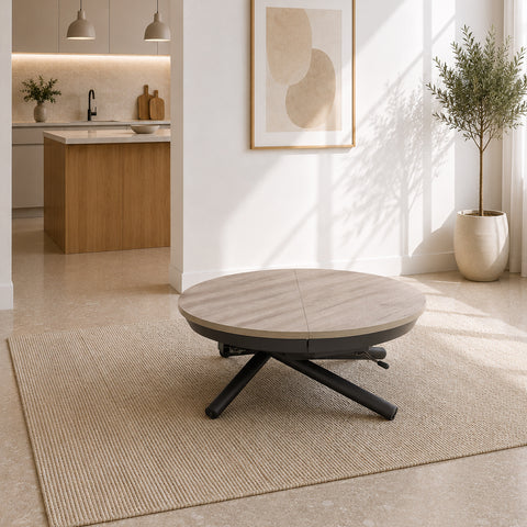 Tavolo trasformabile Elio con piano rotondo effetto quercia e struttura in metallo antracite. Dotato di meccanismo regolabile in altezza e sistema allungabile, si trasforma facilmente da tavolino da salotto a tavolo da pranzo, ideale per ottimizzare gli spazi moderni.